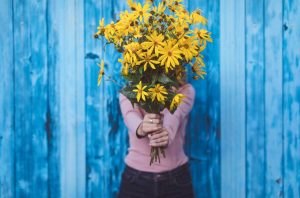 woman holding huge bunch of yellow flowers